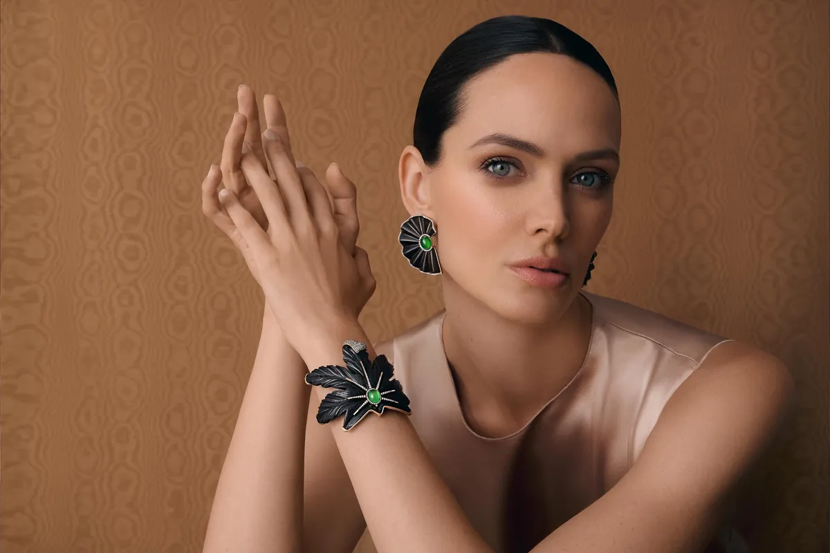 A model wearing a carved dark leaf cuff and matching earrings set with green jadeite from Asprey and Silvia Furmanovich
