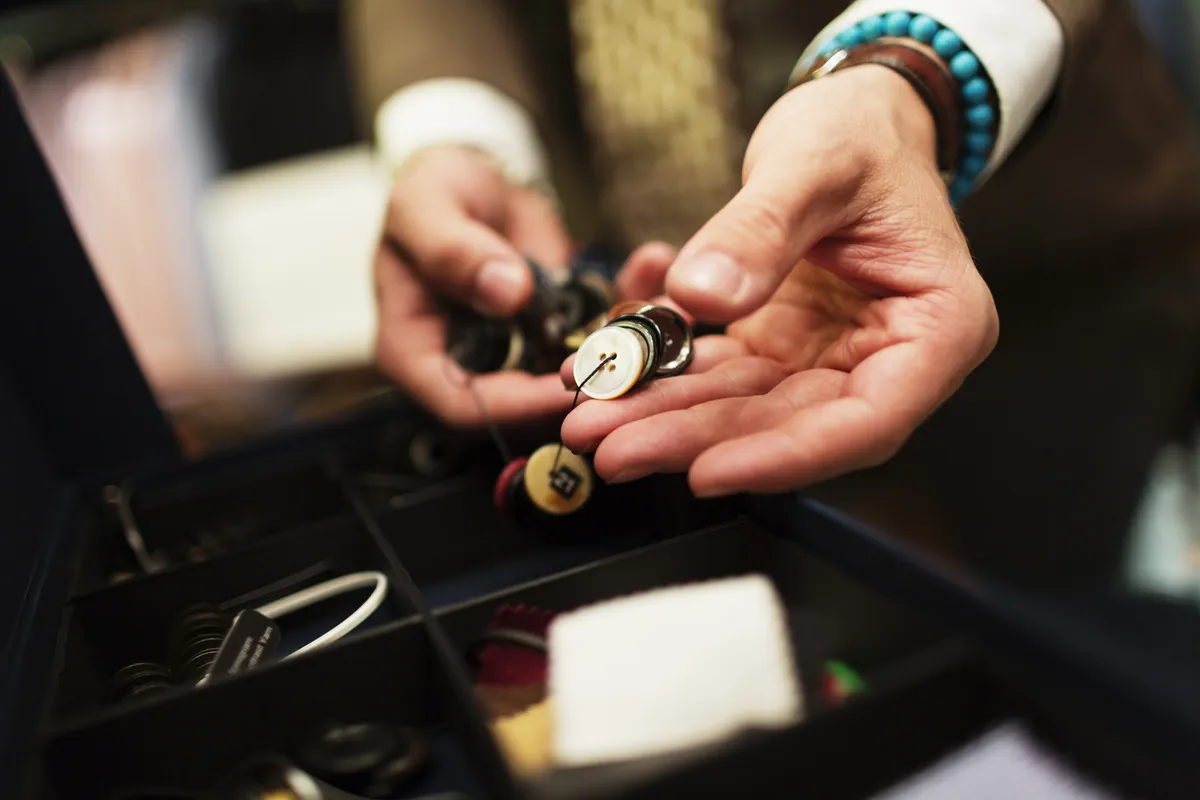 A fashion designer’s hands choosing buttons from a box in a studio