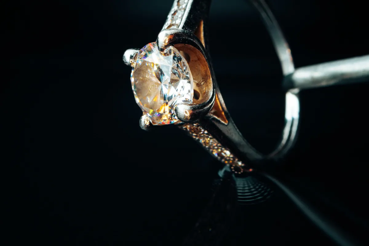 A gold ring set with a diamond, photographed close up on a black background