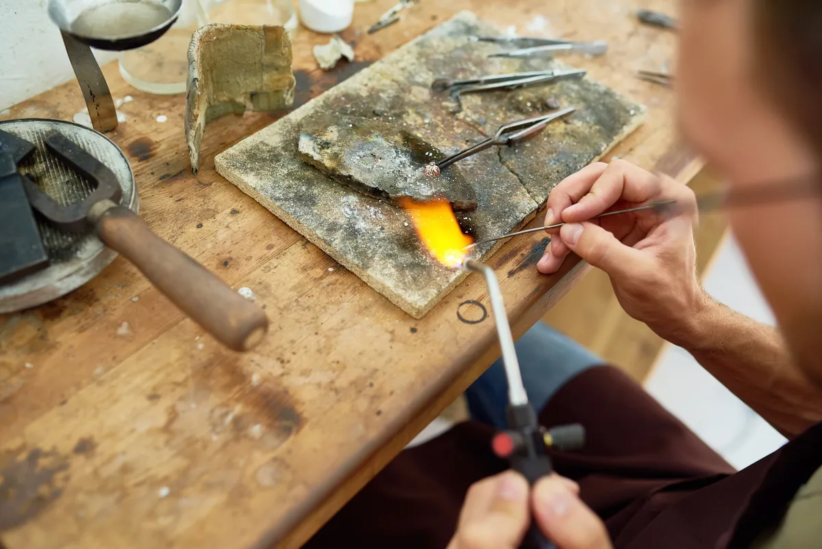 A jeweller working on a ring with a soldering torch