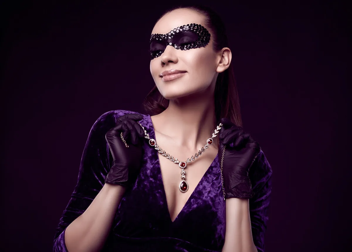 A woman in a purple velvet gown with long black evening gloves and a pendant necklace