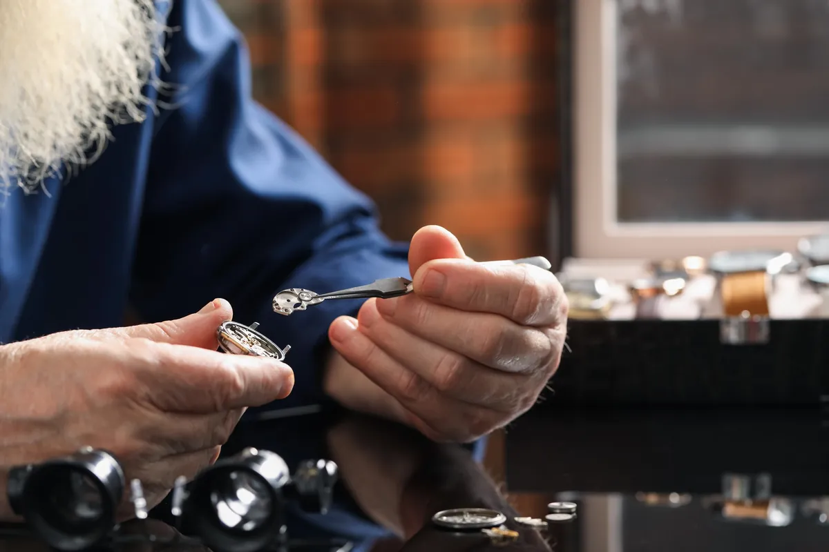 A senior watchmaker carefully repairing a mechanical watch at his bench